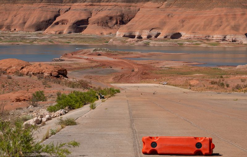 Concrete launch ramp at Bullfrog running toward Lake Powell, an orange barrier across it and open water well past its end.