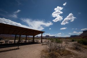 Open-sided shade pavilion with picnic tables at Lower Onion Creek, mesas and cumulus on the skyline beyond.
