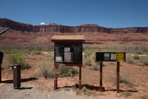 BLM welcome board and a fire-restrictions sign at Lower Onion Creek Campground, red cliffs across the flats behind.
