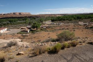 Sand Island from the bench above: ranger buildings, a parking area with trucks, and the San Juan behind cottonwoods.