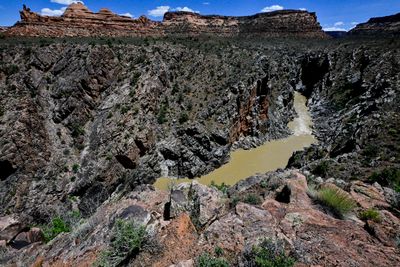 Looking down from a lichen-covered rim into Westwater Canyon's dark, jagged inner gorge