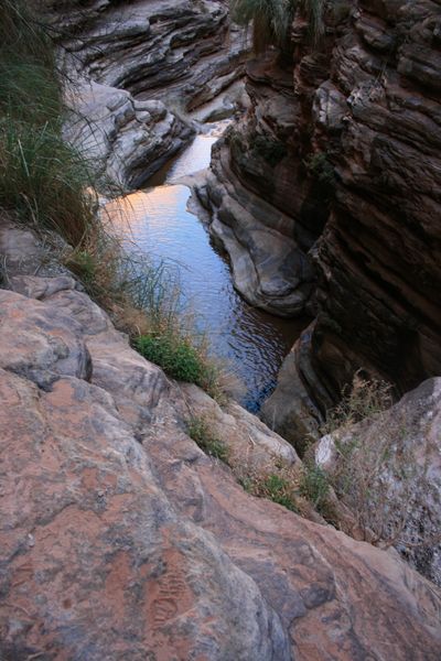 Chained pools in a narrow side canyon reflect warm evening light between polished, layered rock ledges.