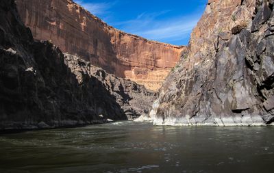Flat green water of the Colorado River between dark fractured metamorphic walls in Westwater Canyon