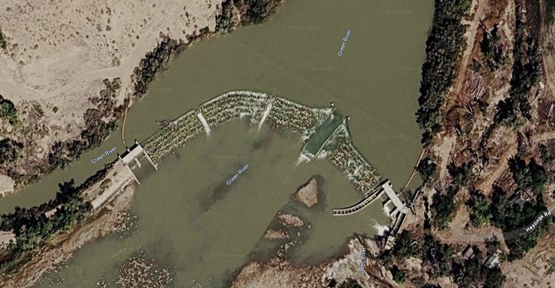 Satellite view of the low diversion weir angling across a bend of the silty Green River near the town of Green River, Utah