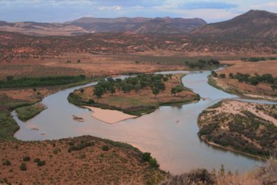 Evening view over a horseshoe bend of the Green River at Rainbow Park, with a cottonwood island, an exposed sandbar