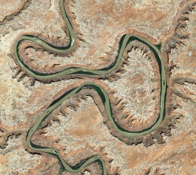 Satellite view of the Green River's entrenched meanders looping around Bowknot Bend in Labyrinth Canyon, the green river corridor winding through bare tan slickrock.
