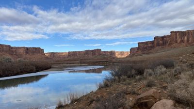 Ice fringes the calm Green River between red sandstone canyon walls in Stillwater Canyon