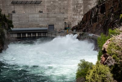 Water surging from the Flaming Gorge Dam spillway at a 9,800 CFS release, green water running fast downstream.