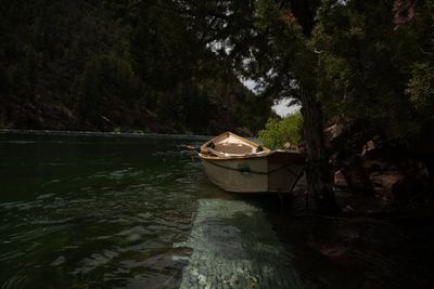 A dory tied up in the shade above the Little Hole trail, clear cobble visible under green tailwater.