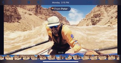Screenshot of a phone playing a shared video: a grinning rower on the oars is surrounded by breaking brown whitewater, with playback controls and a filmstrip visible.