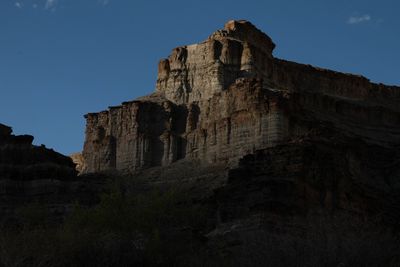 Massive sandstone tower catching the last direct light of the day above a shadowed canyon wall.