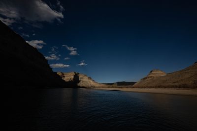 Layered canyon walls curve around a river bend at dusk, catching the last reflected light off the water.