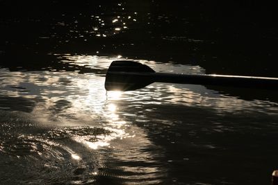 Close view of an oar blade pulling through water lit gold by late sun.