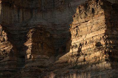Warm light rakes across eroded sandstone towers, revealing alcoves and vertical joints.