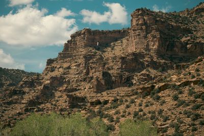 A cliff face pocked with alcoves and dotted with juniper.