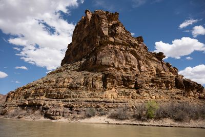 A massive isolated butte seen from river level, with stepped erosion and horizontal bedding.