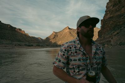 Crew member holding a beer on the raft in the evening, canyon walls catching the last warm light.