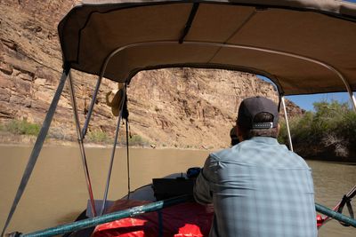 Two crew members rowing a loaded raft through a narrowing sandstone canyon.