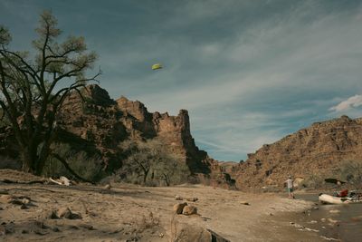A kite high above the canyon rim, seen from a beach stop with cottonwoods and red rock towers.