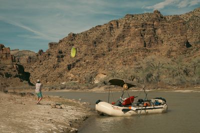 Kite flying over the river with the full canyon backdrop, the rigged raft waiting at the water's edge.