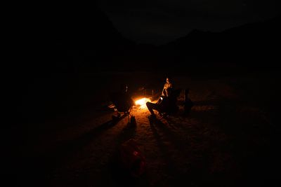 A campfire burning low at night with canyon walls faint in the darkness.