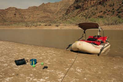 Loaded raft parked on a wide sandy beach with a shade canopy up and bocce balls on the sand.