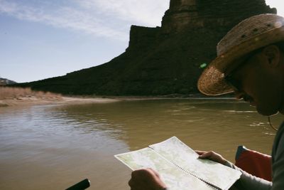River runner reading a spiral-bound river map below a massive butte.