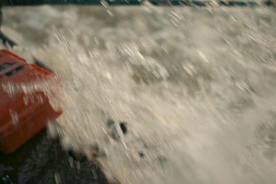 Whitewater exploding over the bow of the raft in a rapid, an orange dry box in the spray.