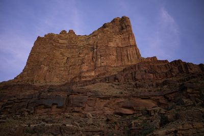 A tall layered sandstone butte catches last light beneath a deep purple dusk sky.