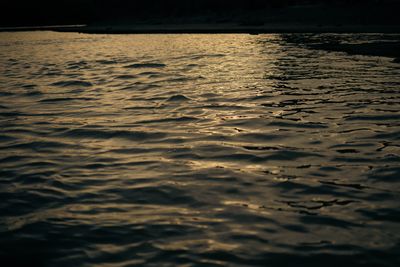 Low sun scatters gold across rippled river water below a dark shoreline.