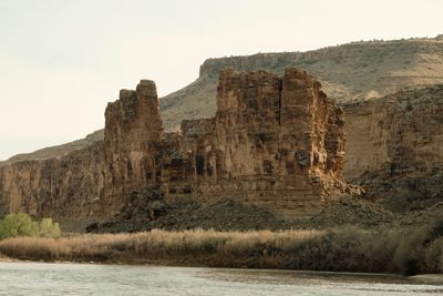 A massive sandstone fortress rising from the river, vertical columns and buttresses.