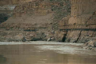 A dark shale band meets sandstone above where the river cuts the contact zone, whitewater at the base.