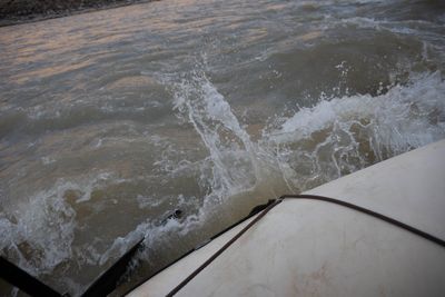 Whitewater splashes over the tube of a raft as it pushes through a wave.