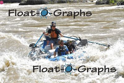 A blue oar raft punches head-on into a silty whitewater rapid on the Snake River, the rower braced upright on both oars in an orange PFD, a standing crew member behind him and two crew ducked low in the bow as spray breaks over the tubes.