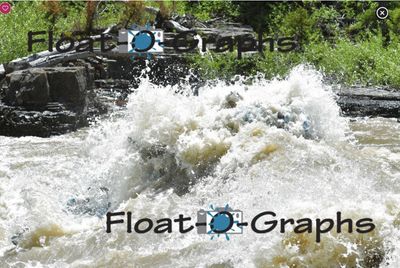 An exploding wall of tan and white whitewater fills the frame of a Snake River rapid, only a blur of blue raft tube and a hint of a blue helmet visible inside the foam, with a dark bedrock shelf, bleached driftwood and green brush along the bank behind.