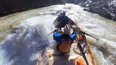 Rower digs both oars in as a wooden dory punches head-on into a foaming wave pile at the bottom of Sock-It-To-Me rapid, Westwater Canyon.
